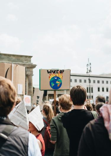 Vor dem Brandenburger Tor demonstrieren jungen Menschen für mehr Klimaschutz. Ein Plakat zeigt eine Erde in Flammen mit dem Text WAKE UP.