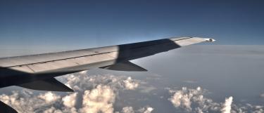 Aircarft wing view at sunset over clouds and sea